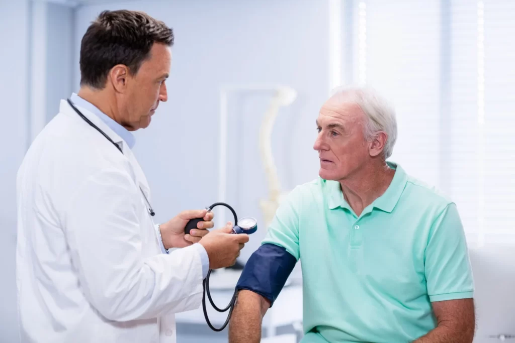 Cardiologista verificando o risco de pressão alta de paciente idoso em consultório médico