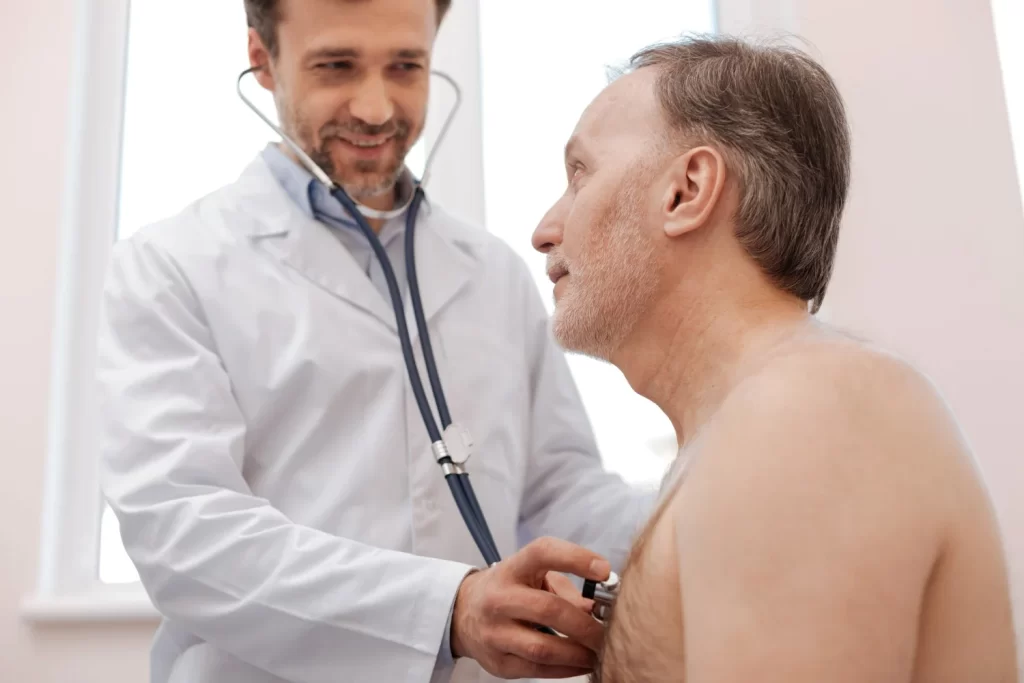 Idoso sendo examinado por cardiologista enquanto o médico usa um estetoscópio
