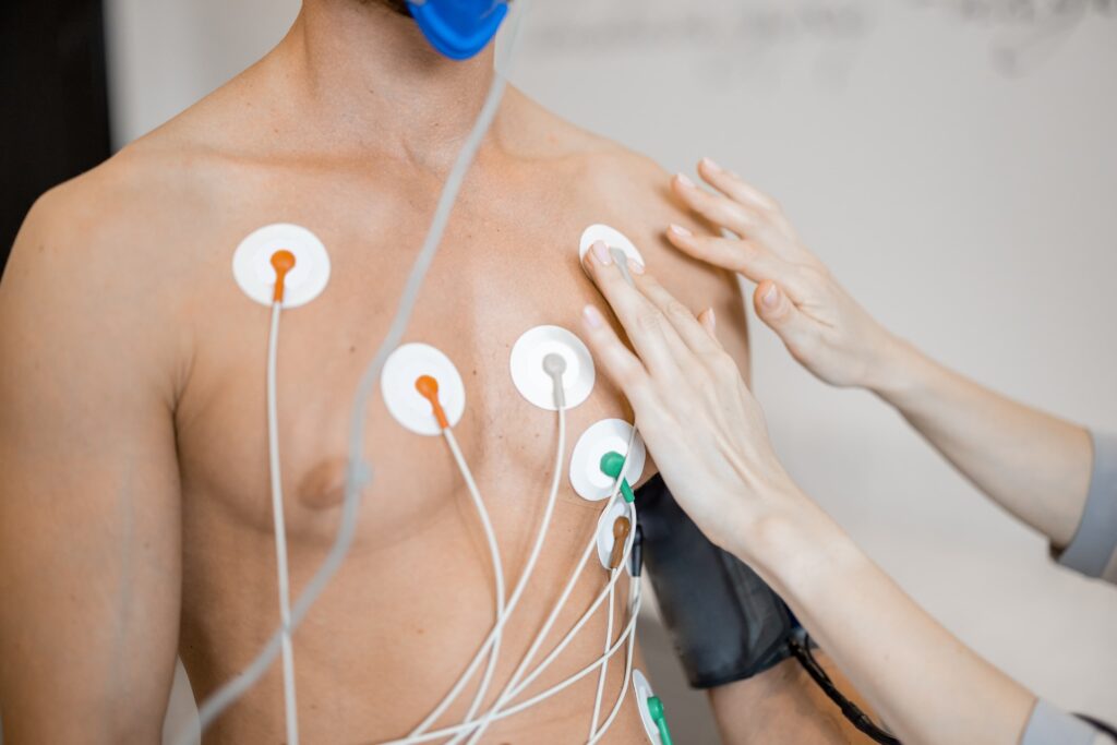 Homem com eletrodos conectados no peito durante exame de Holter em consultório