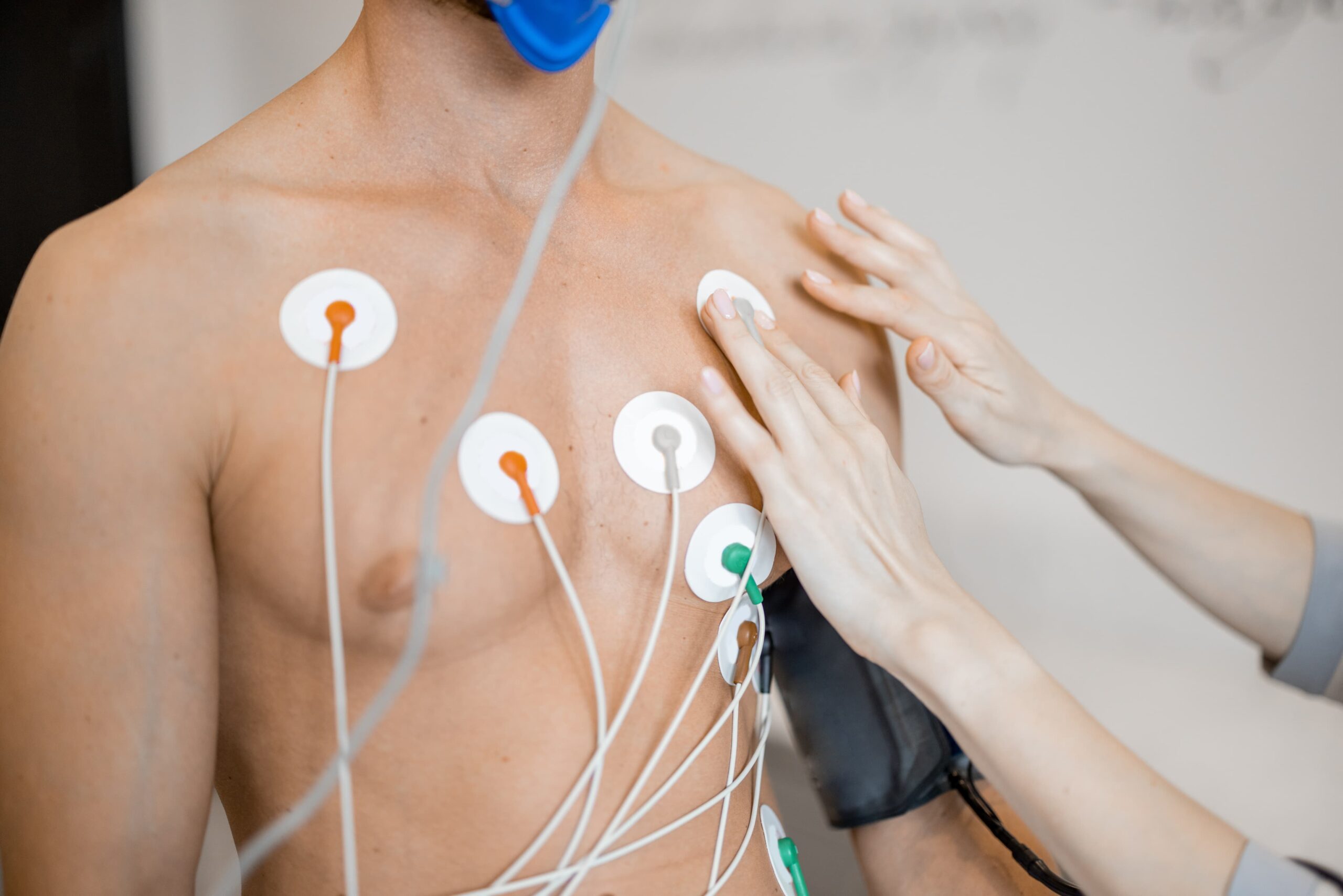 Homem com eletrodos conectados no peito durante exame de Holter em consultório